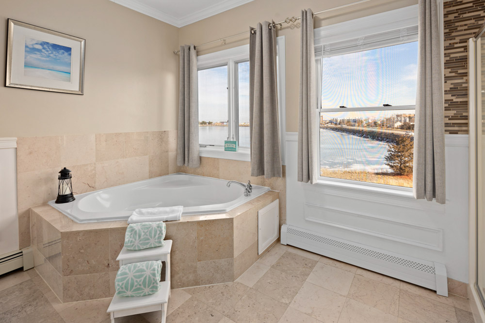 beacon waterfront inn guestroom with bed, spa tub with view